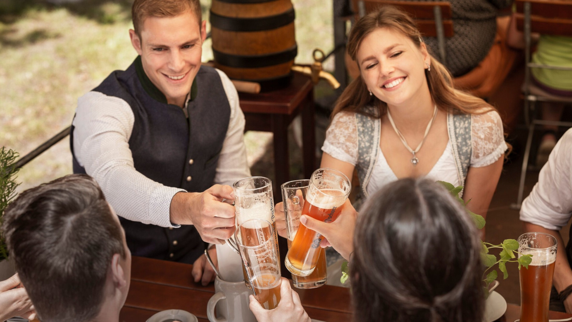 Freunde stoßen im Biergarten mit Bier an